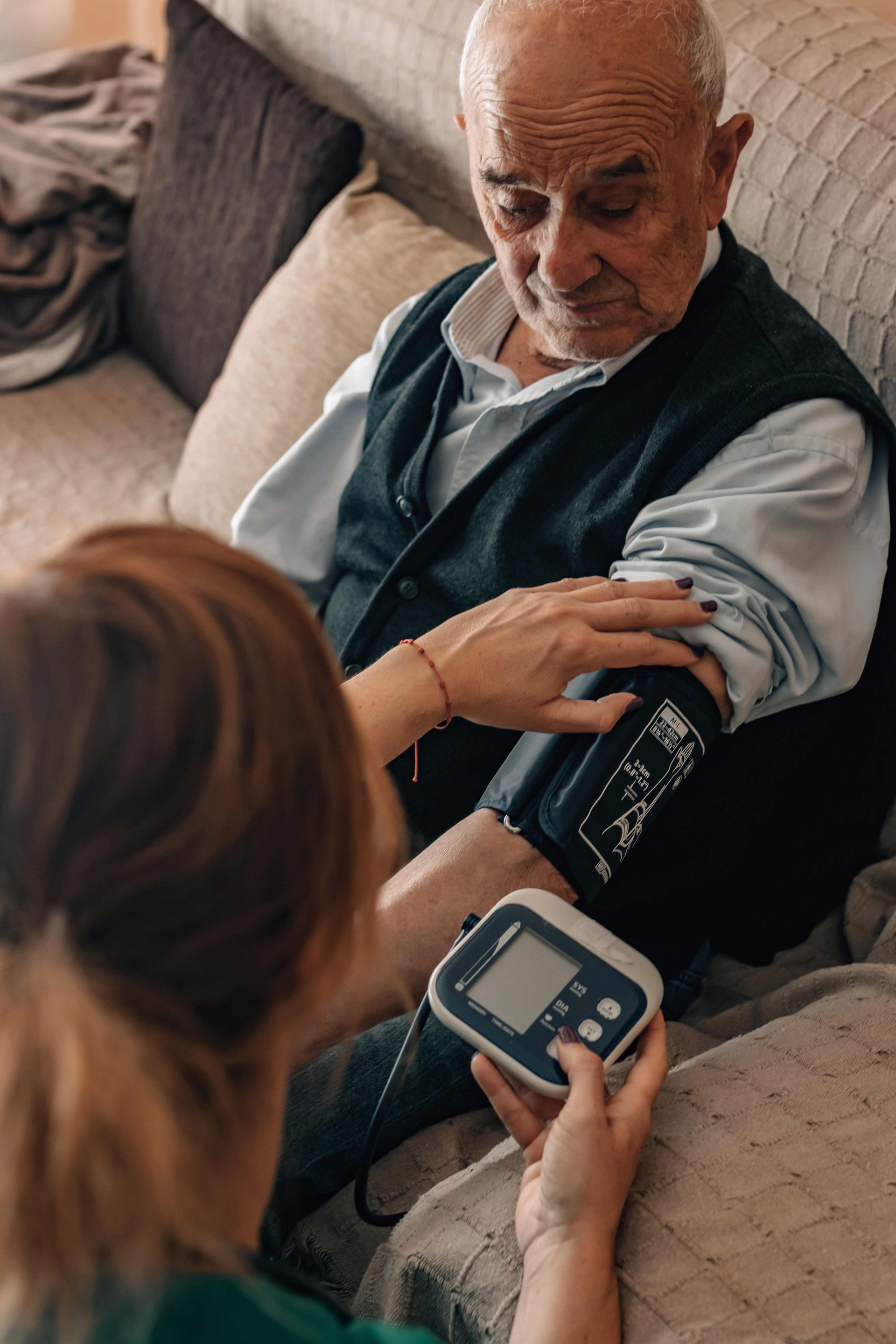 healthcare professional in uniform and wearing a stethoscope takes an elderly person's blood pressure
