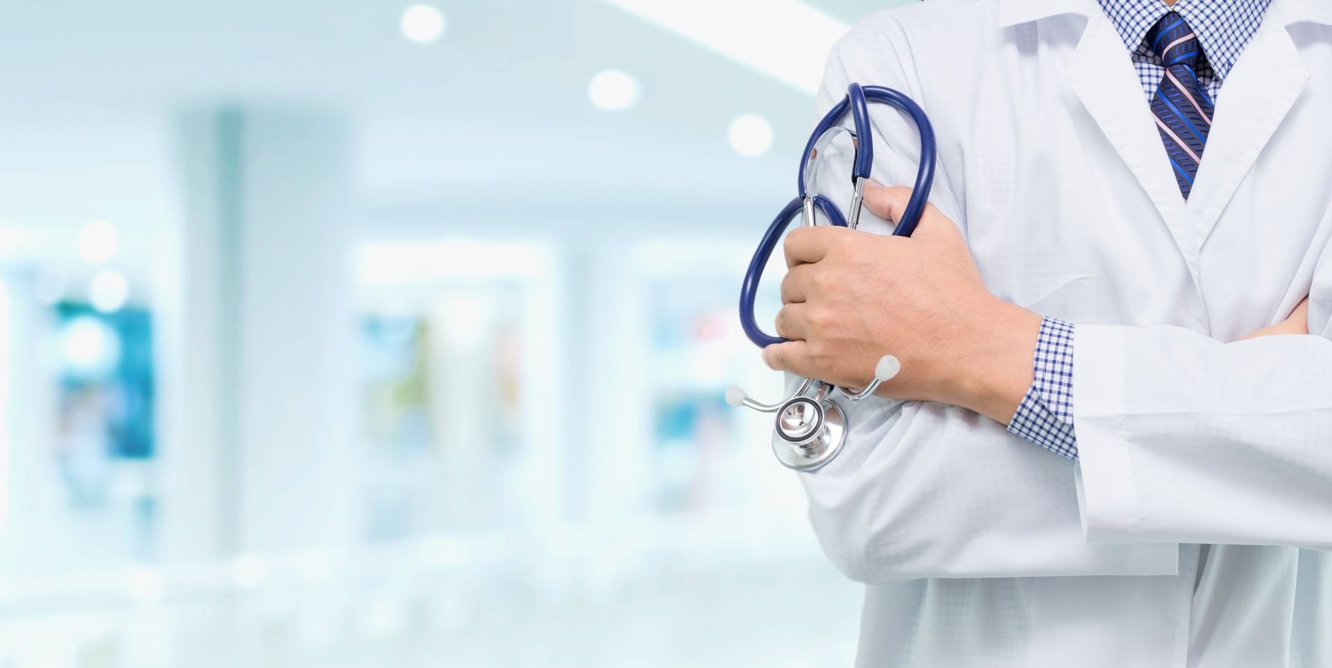Doctor with a stethoscope in the hands behind the hospital background.