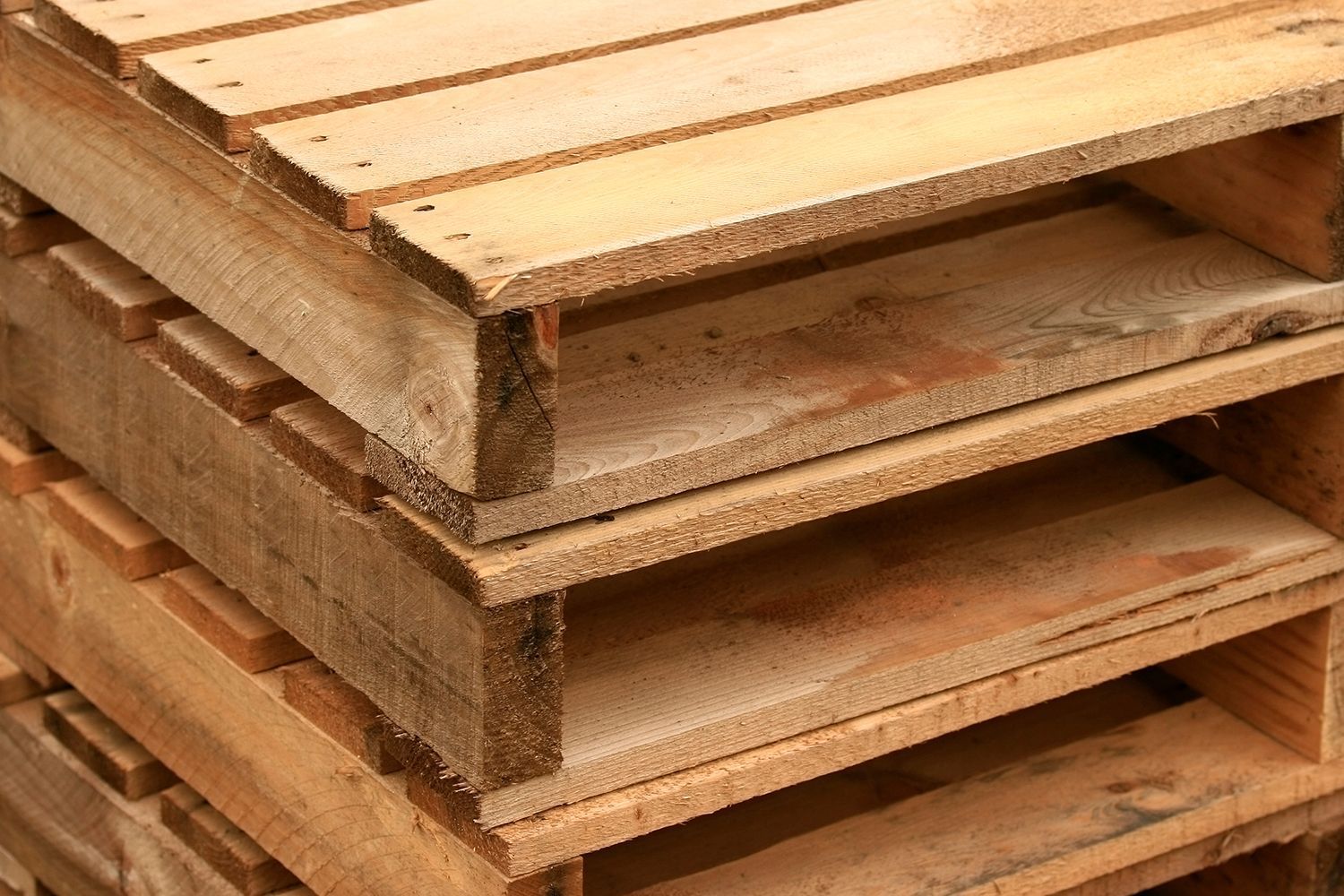 Stacked wood pallets in storage highlighting an experienced pallets and skids provider operation. Stacked wood pallets in storage highlighting an experienced pallets and skids provider operation.