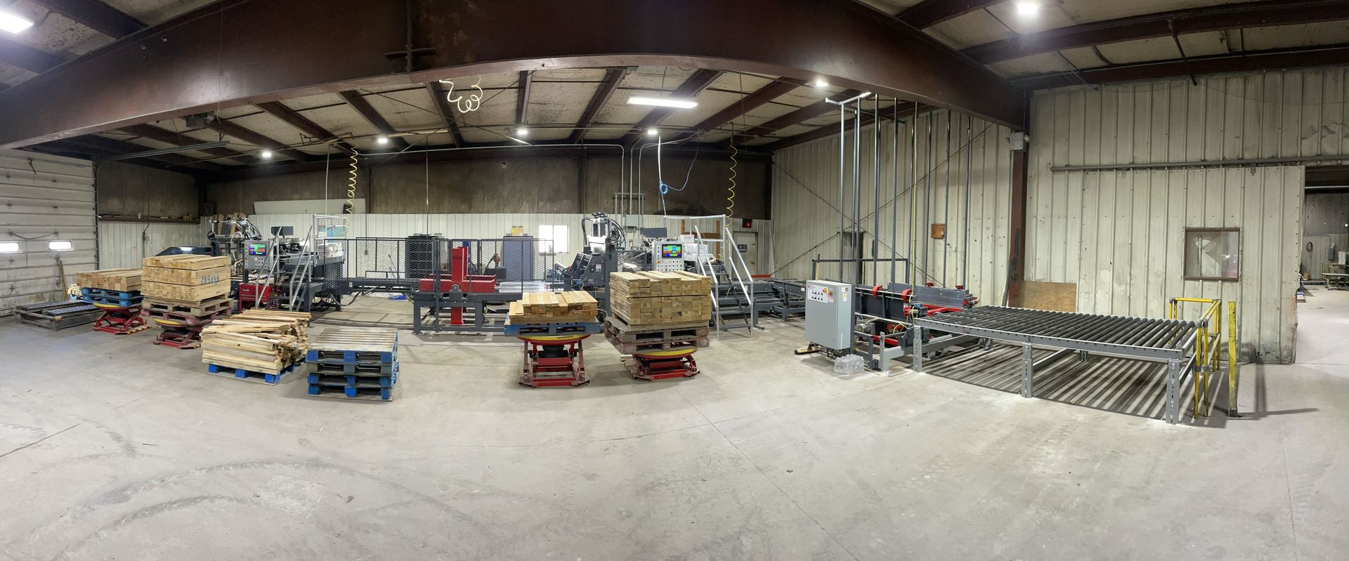 A large warehouse filled with lots of machinery and pallets.