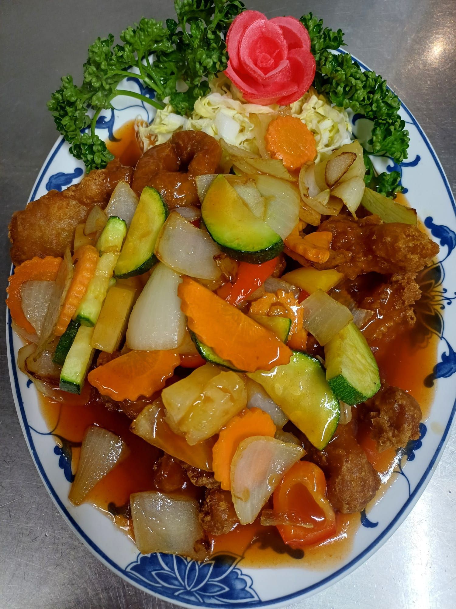 Ein weißer Teller mit Hühnchen und Gemüse auf einem Holztisch.