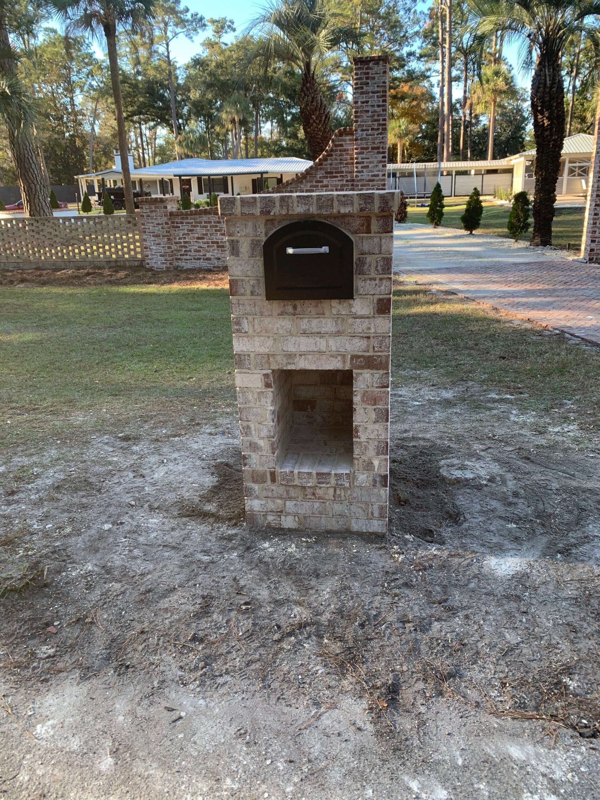 A brick oven is sitting in the middle of a yard.