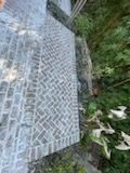 A person is standing on a brick walkway in the woods.