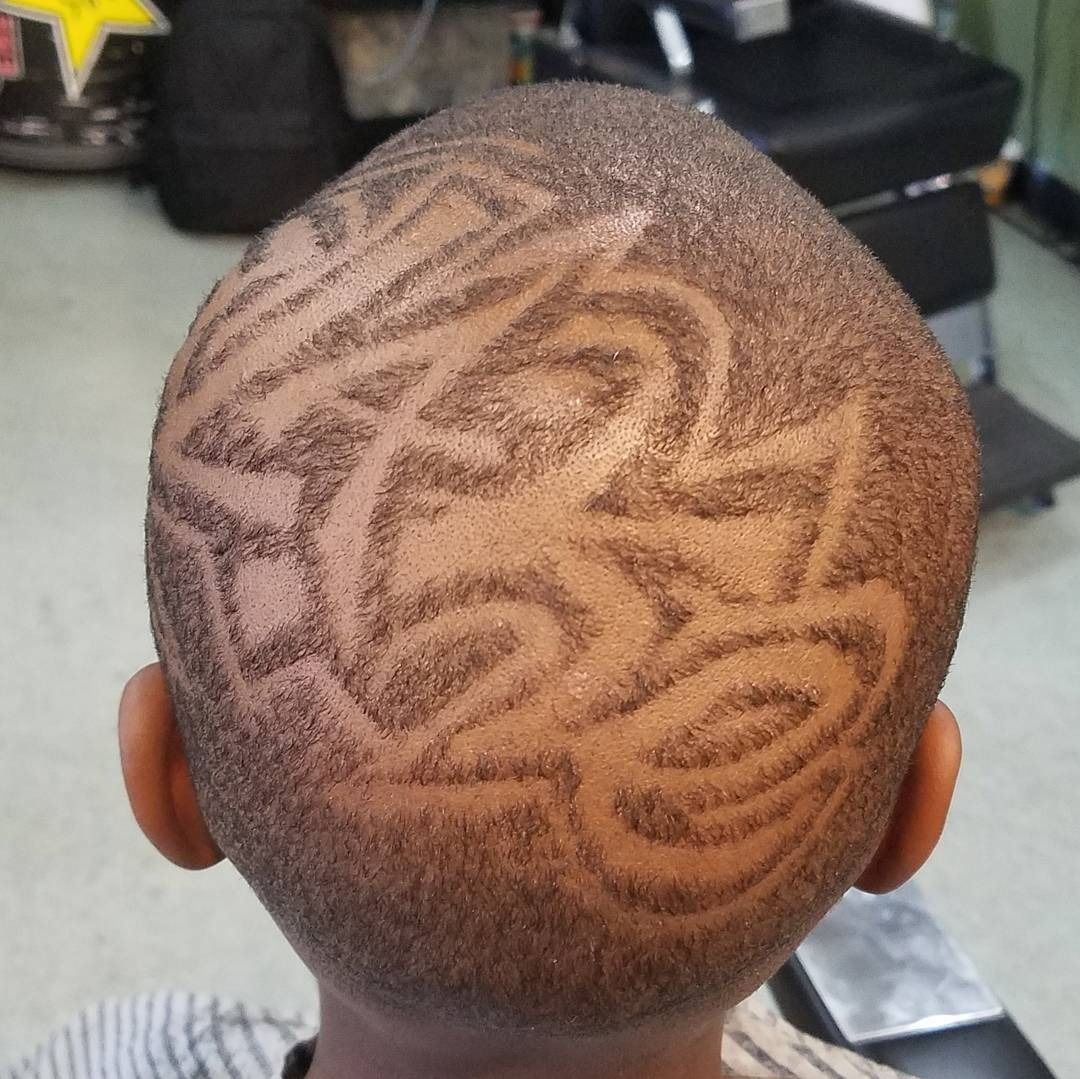 Back of a person's head with a shaved geometric hair design in brown and black tones
