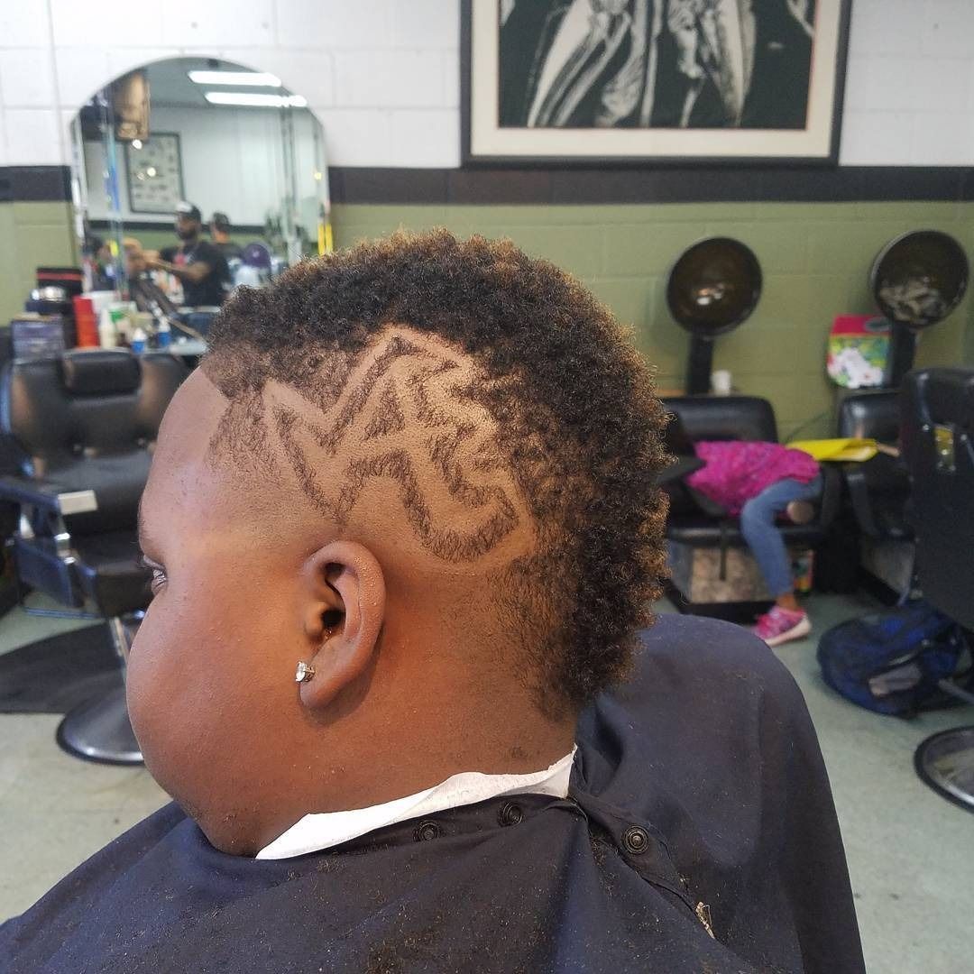 Close-up of a person with a patterned fade haircut in a barbershop chair