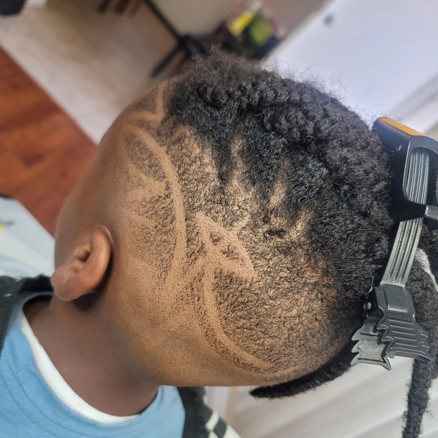Child with braided hairstyle and hair clip, viewed from above in a salon chair