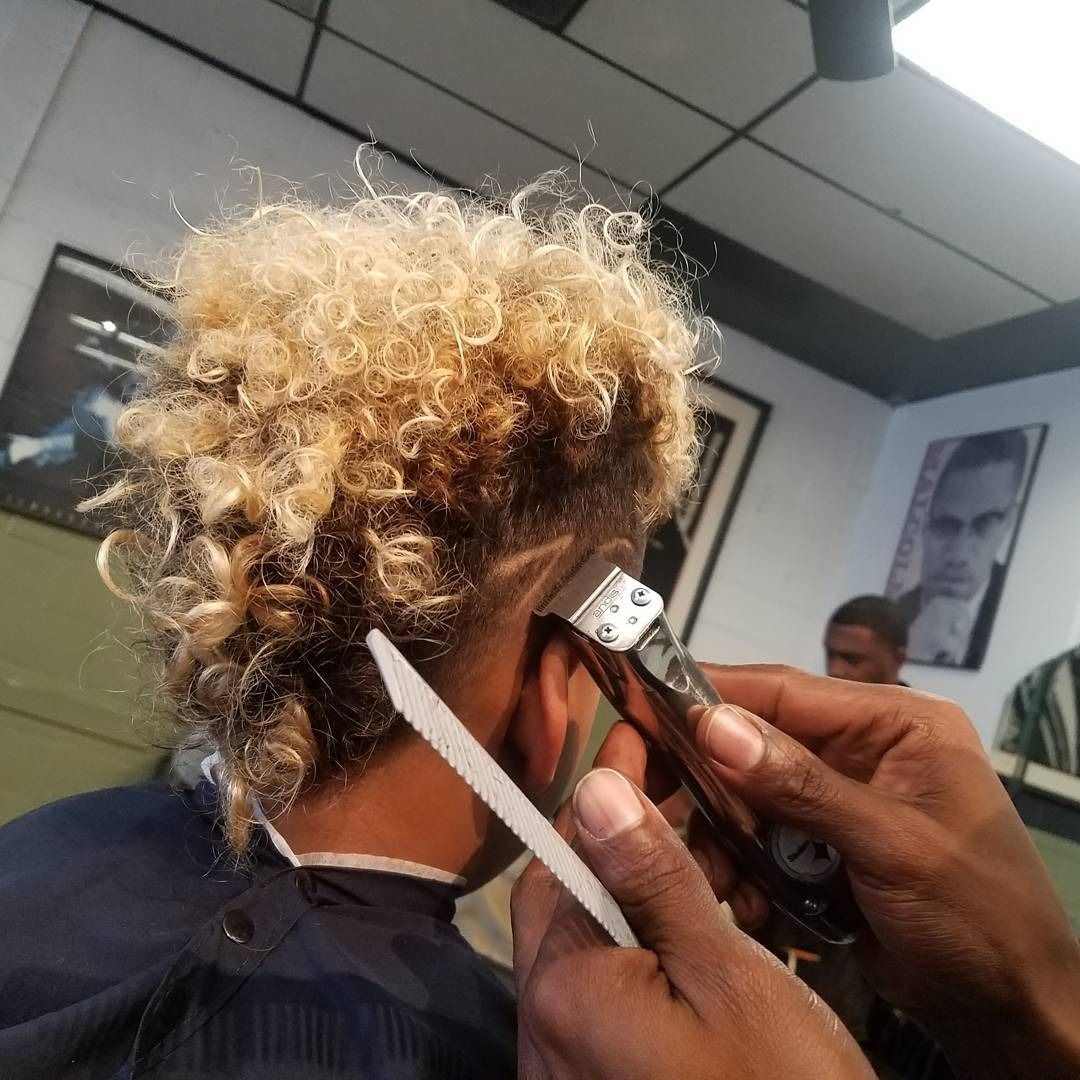 Hairdresser trimming curly blonde hair with clippers and scissors in a salon