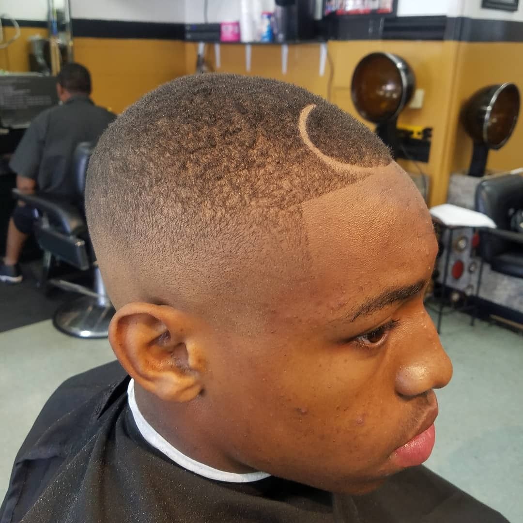 Close-up of a fresh fade haircut with a shaved curved line, seen in a barbershop chair