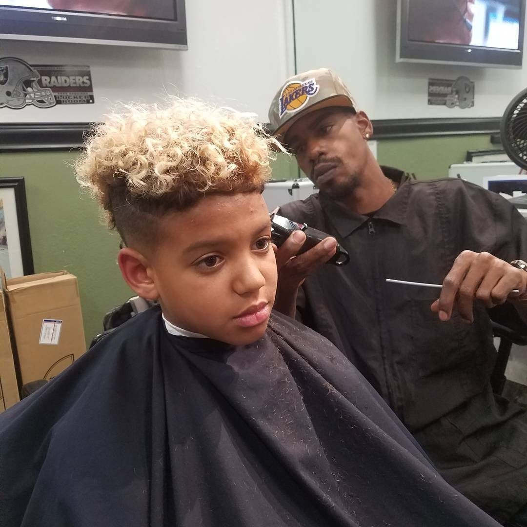 Haircut in progress at a barbershop, with a barber trimming a client’s curly hair.