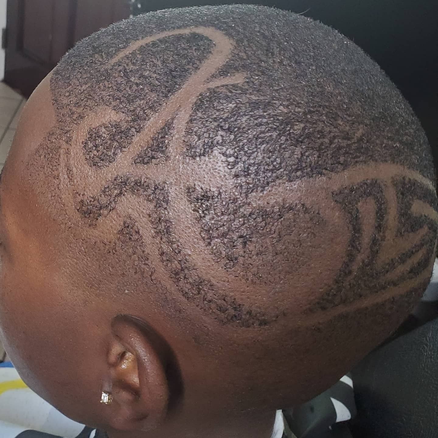 Close-up of a shaved head with intricate geometric hair designs shaved into the scalp.