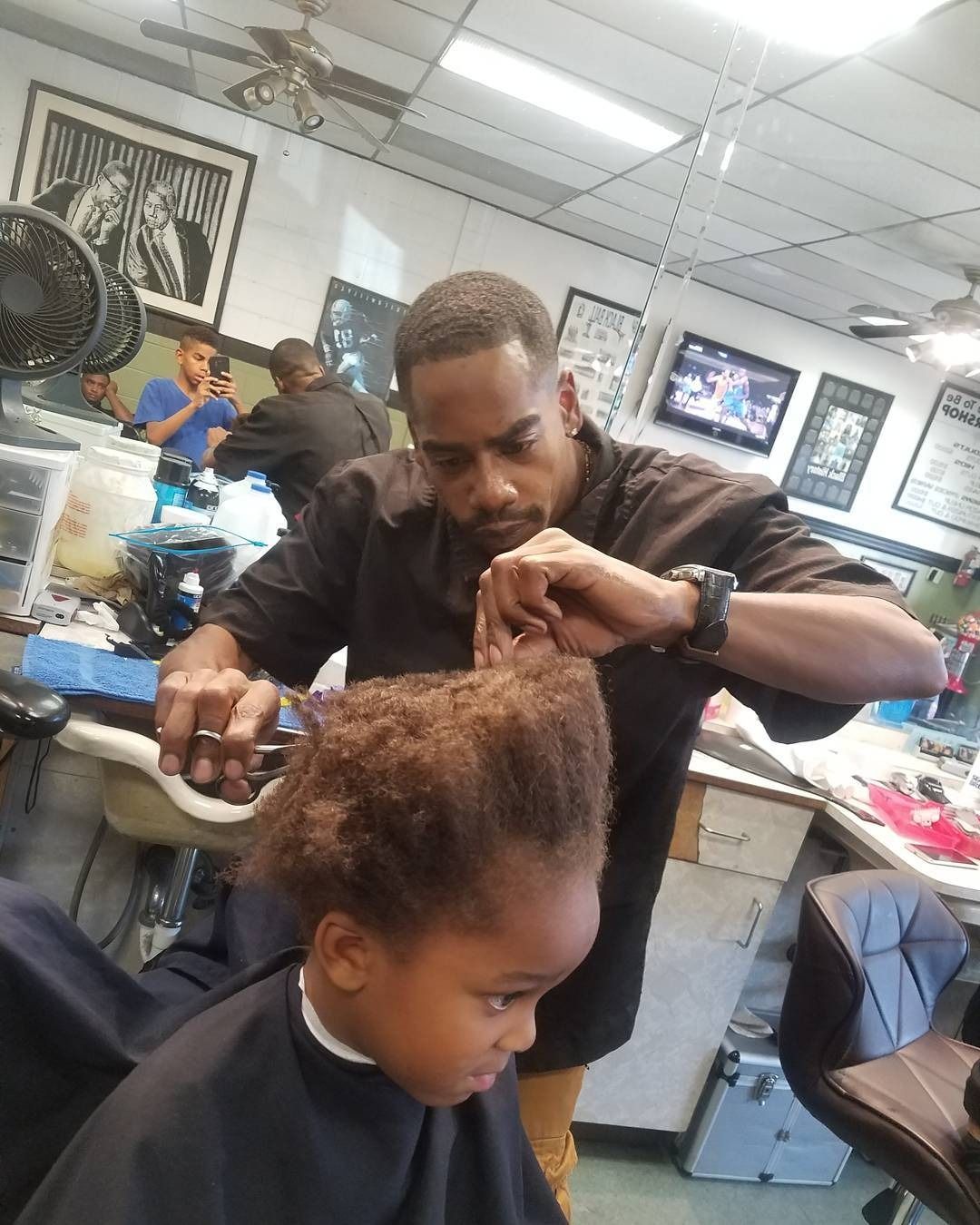 Barber trimming a child’s hair in a busy barbershop