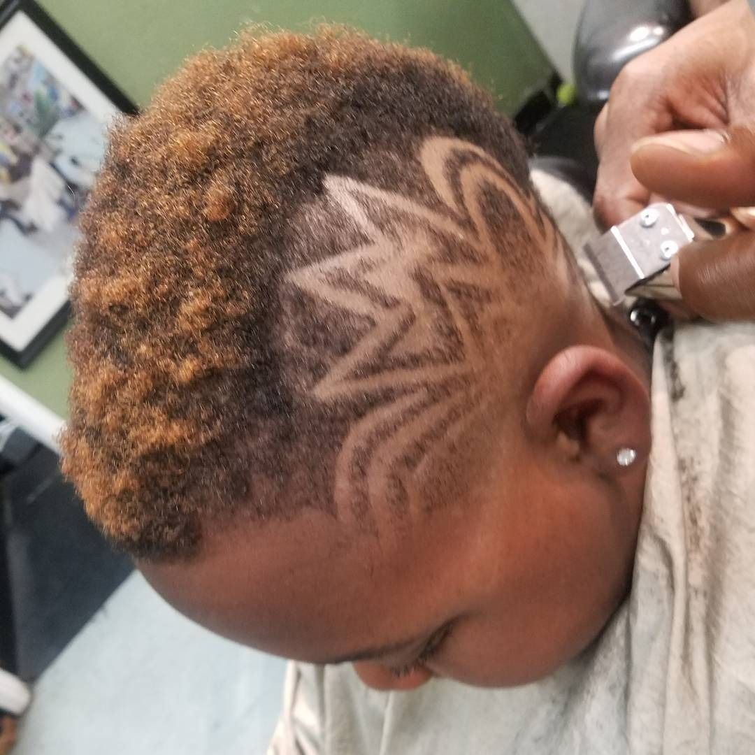Short curly haircut with a shaved star design on the side, shown in a salon chair.