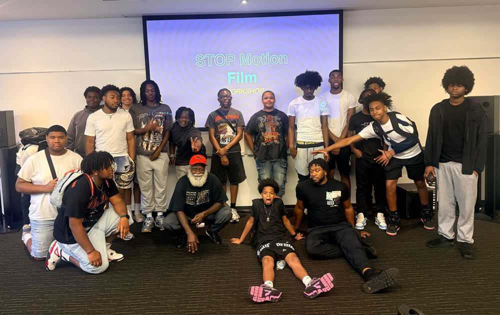 Group posing for a photo in a room with a projected screen backdrop.