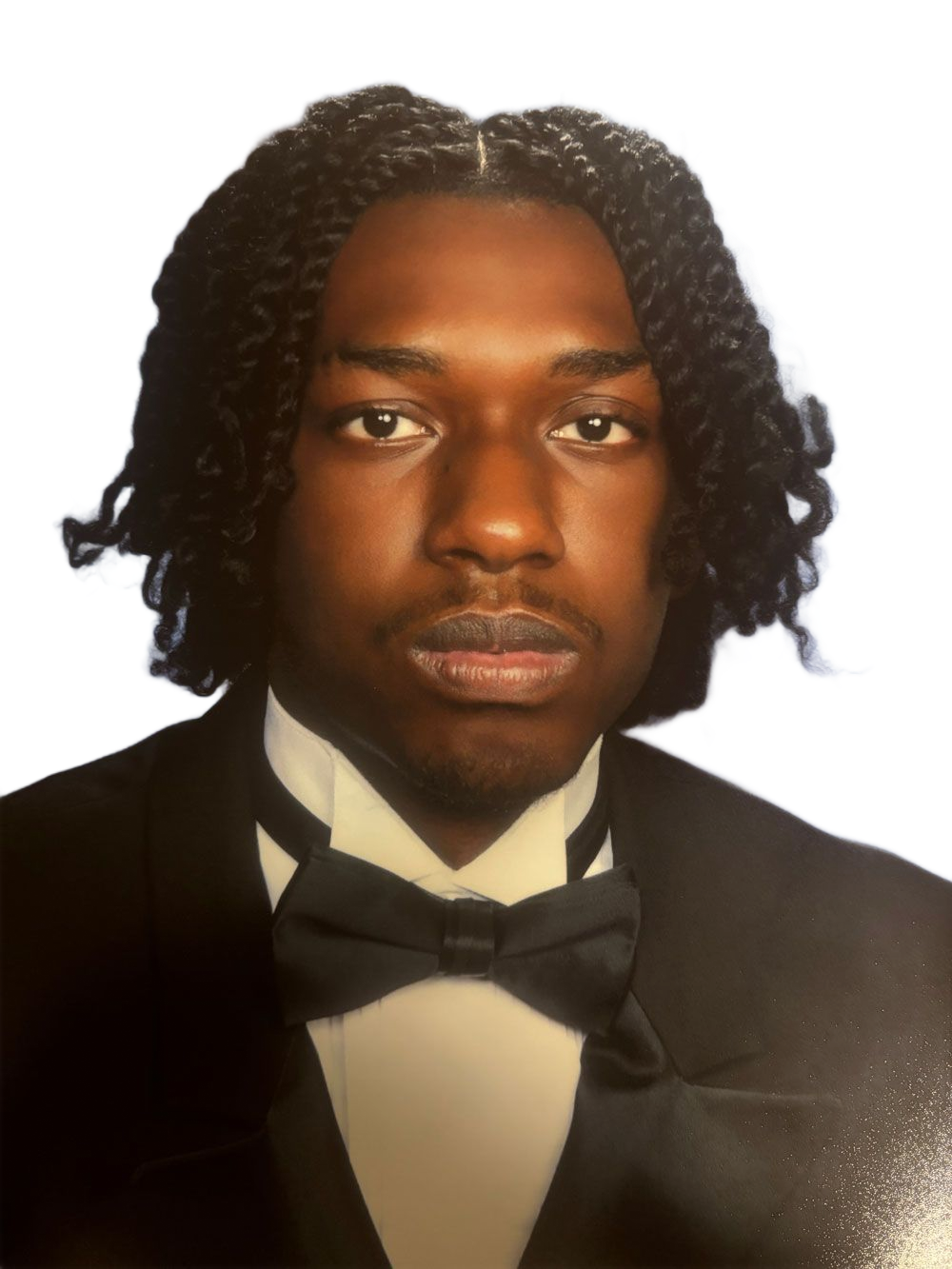 Formal portrait of a person in a black tuxedo and bow tie against a blue studio backdrop