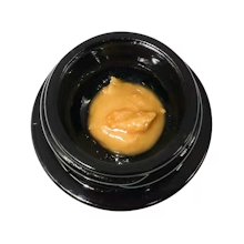Black cosmetic jar with beige cream inside
