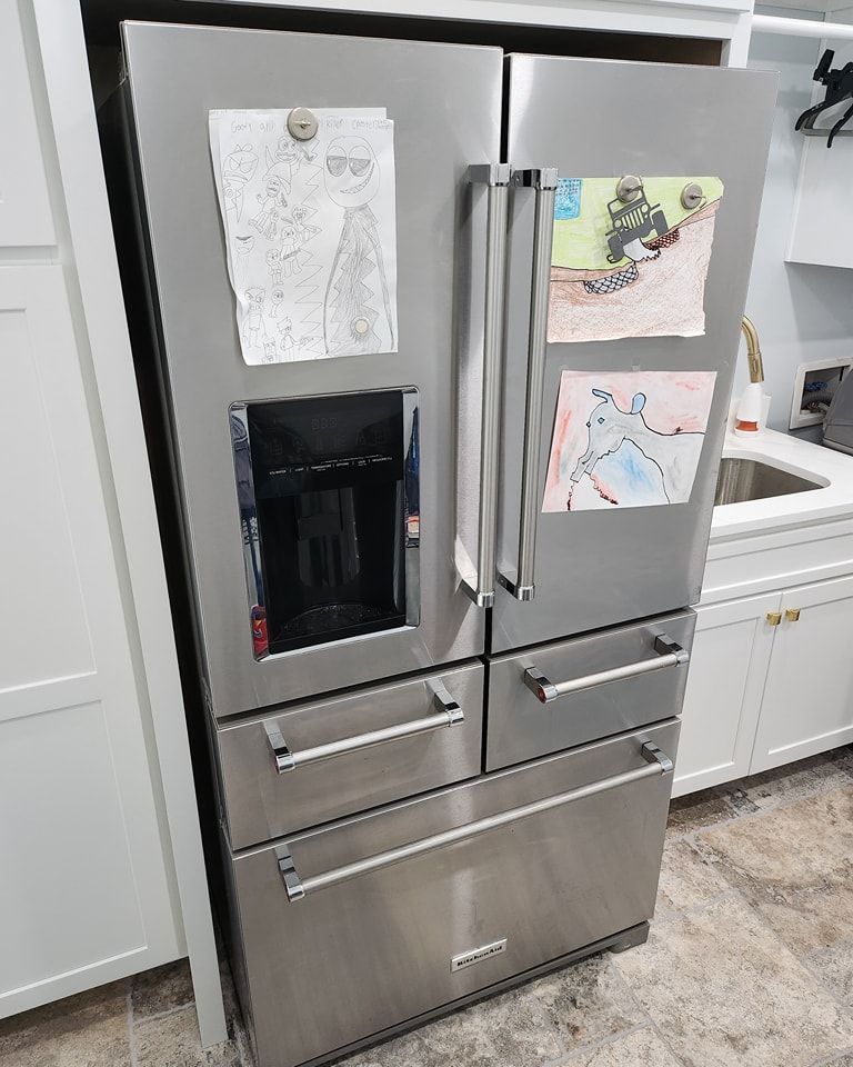 A stainless steel refrigerator is sitting in a kitchen next to a sink.