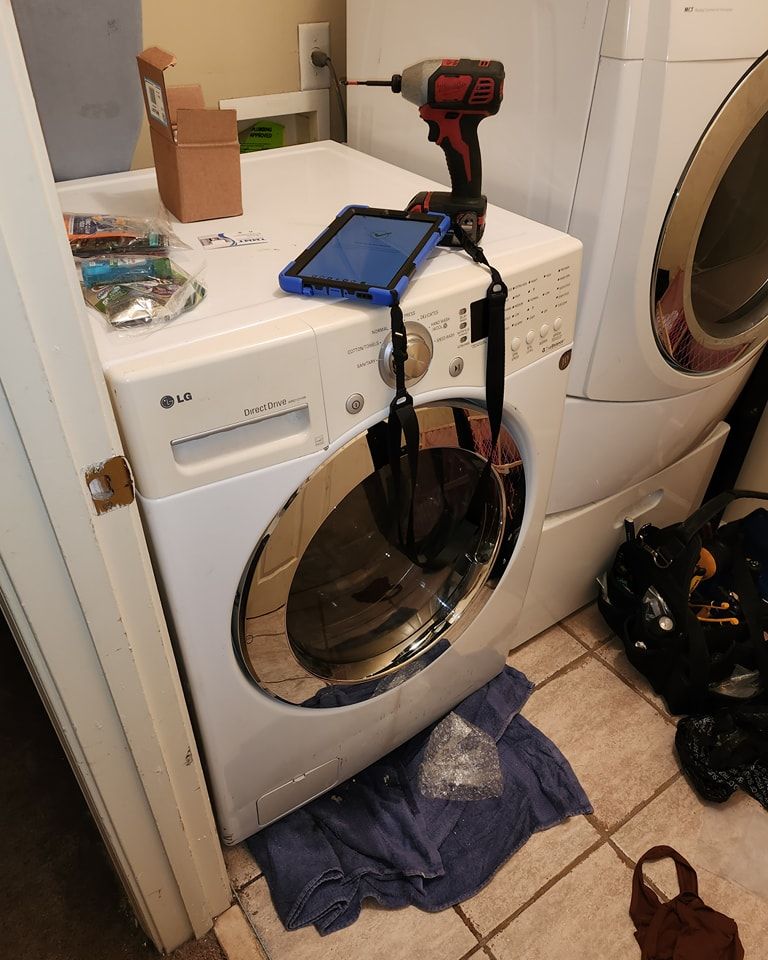 A washer and dryer in a laundry room with a tablet on top of it