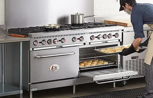 A man is taking a tray of food out of an oven.