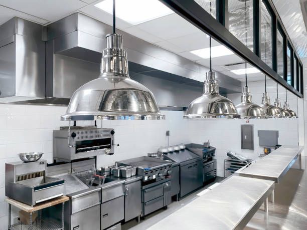 A kitchen with stainless steel appliances and pendant lights hanging from the ceiling.
