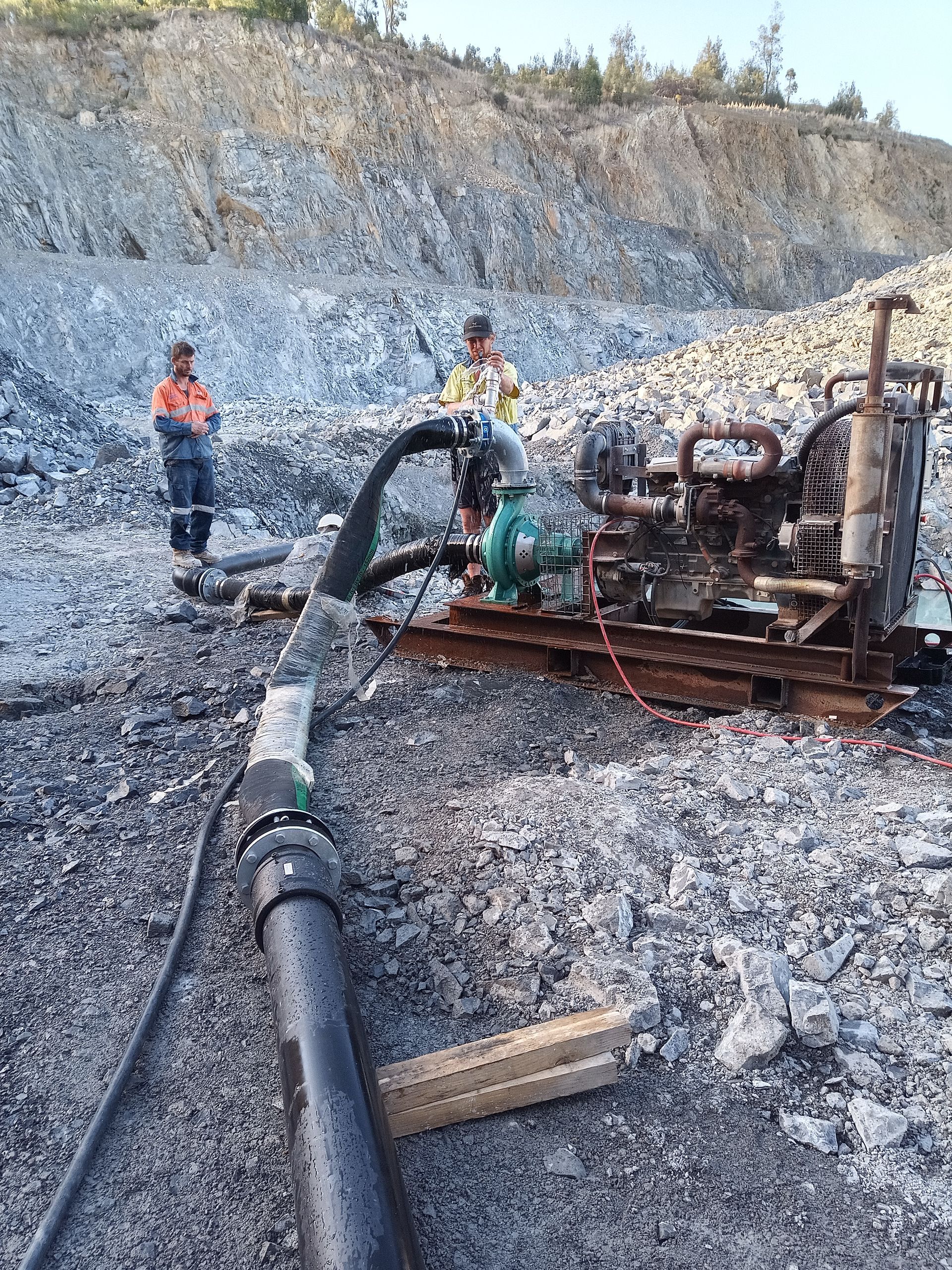 A man is standing next to a machine in a rocky area. — Midcoast Irrigation & Horticultural Supplies In Taree, NSW