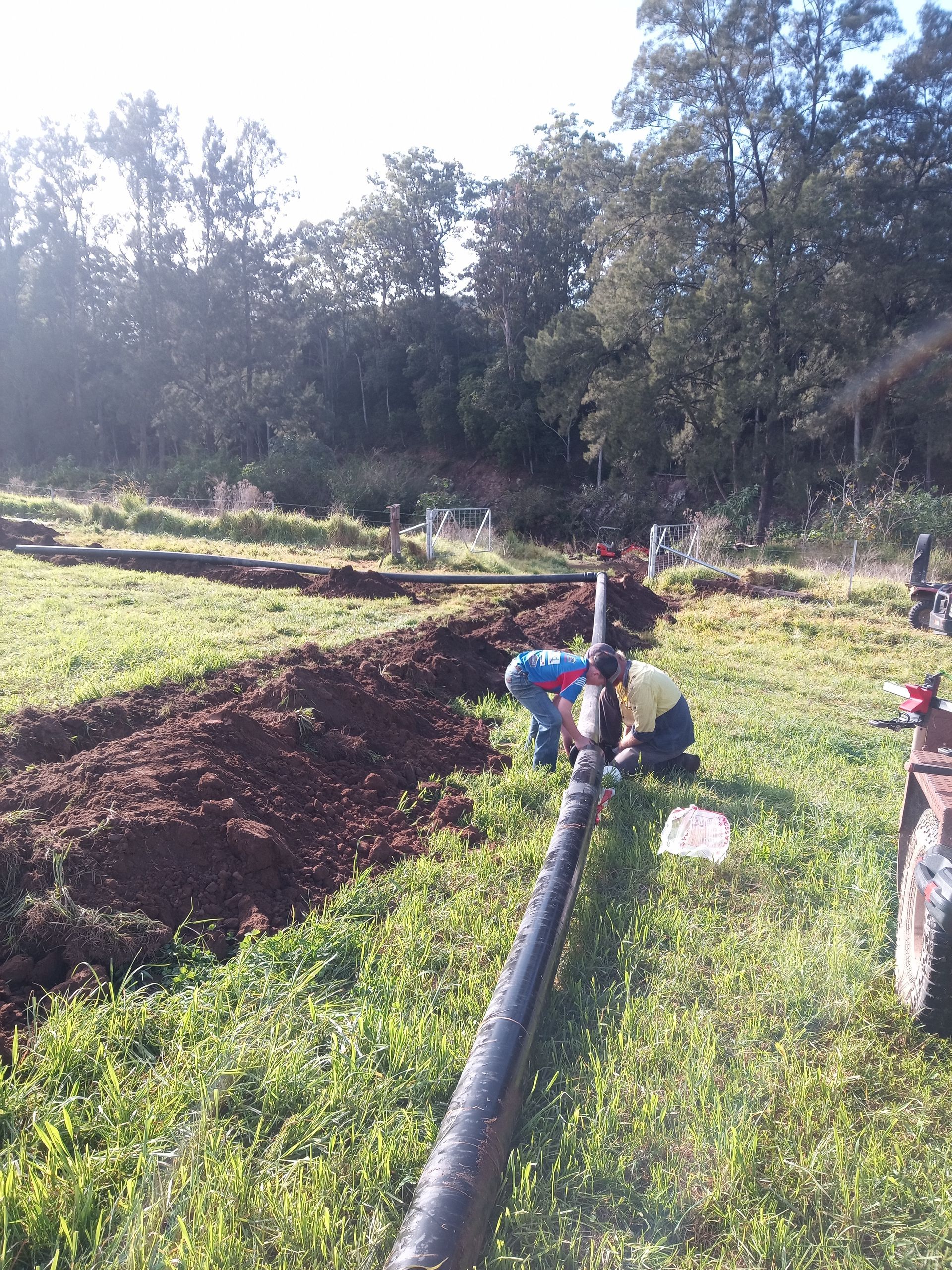 A group of people are working on a pipe in a field.— Midcoast Irrigation & Horticultural Supplies In Wauchope, NSW
