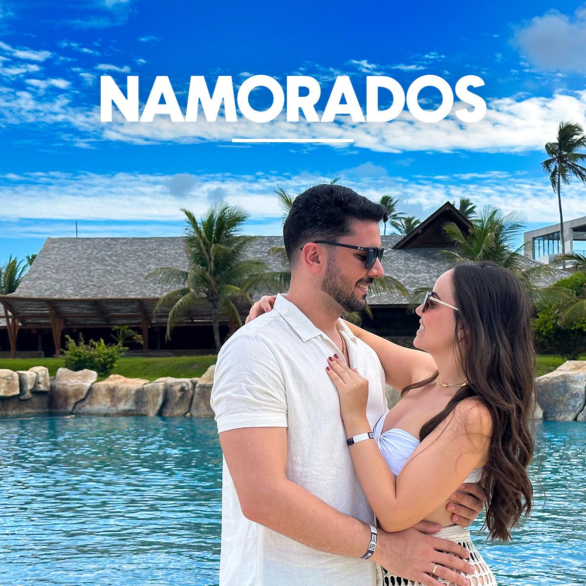 Casal apaixonado e sorridente abraçado em frente à piscina do resort Enotel em um dia de céu azul com nuvens. No topo da imagem, a palavra Namorados aparece em destaque junto a faixas da campanha My Black, e no canto inferior esquerdo, há um selo laranja informando 