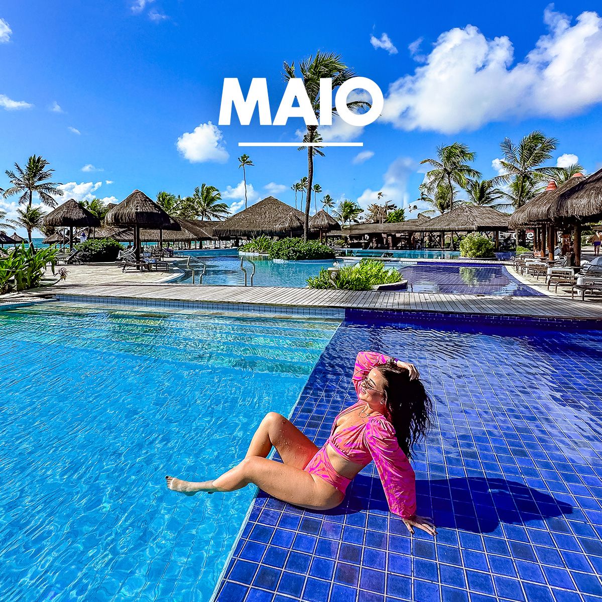 Mulher de biquíni rosa relaxando na parte rasa de uma grande piscina de azulejos azuis no resort Enotel, com quiosques e coqueiros ao fundo sob um céu ensolarado. No topo, a palavra Maio aparece em destaque junto a faixas da campanha My Black, e no canto inferior esquerdo, há um selo laranja informando 