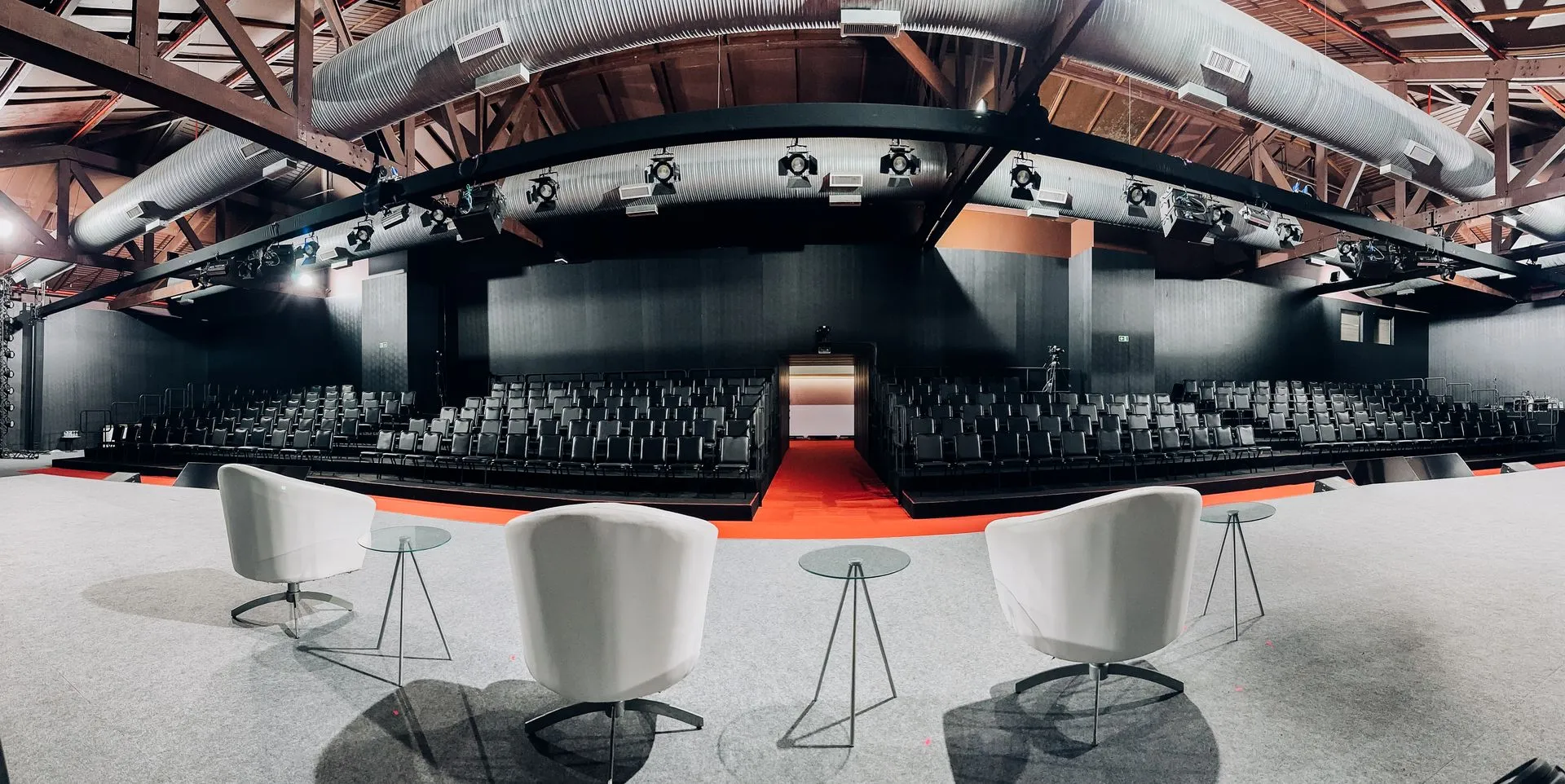 Convention room in auditorium setup with rows of chairs under wooden beams.