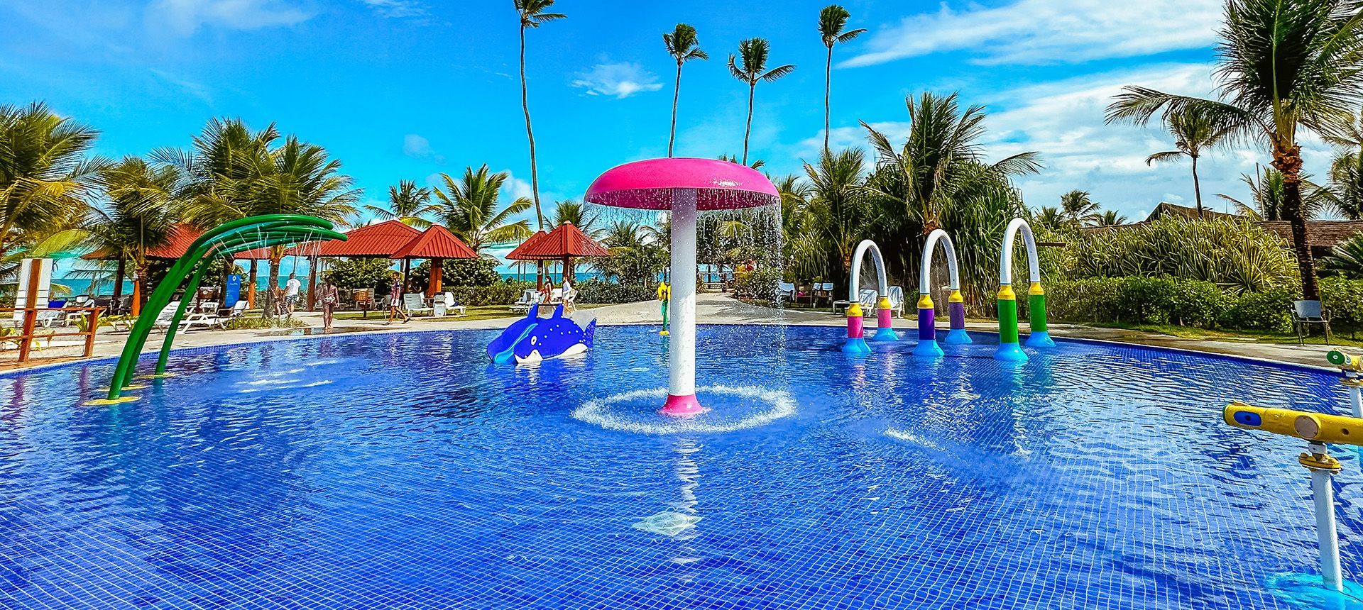 Piscina infantil de parque acuático con fuente de hongo rosa y juguetes interactivos.