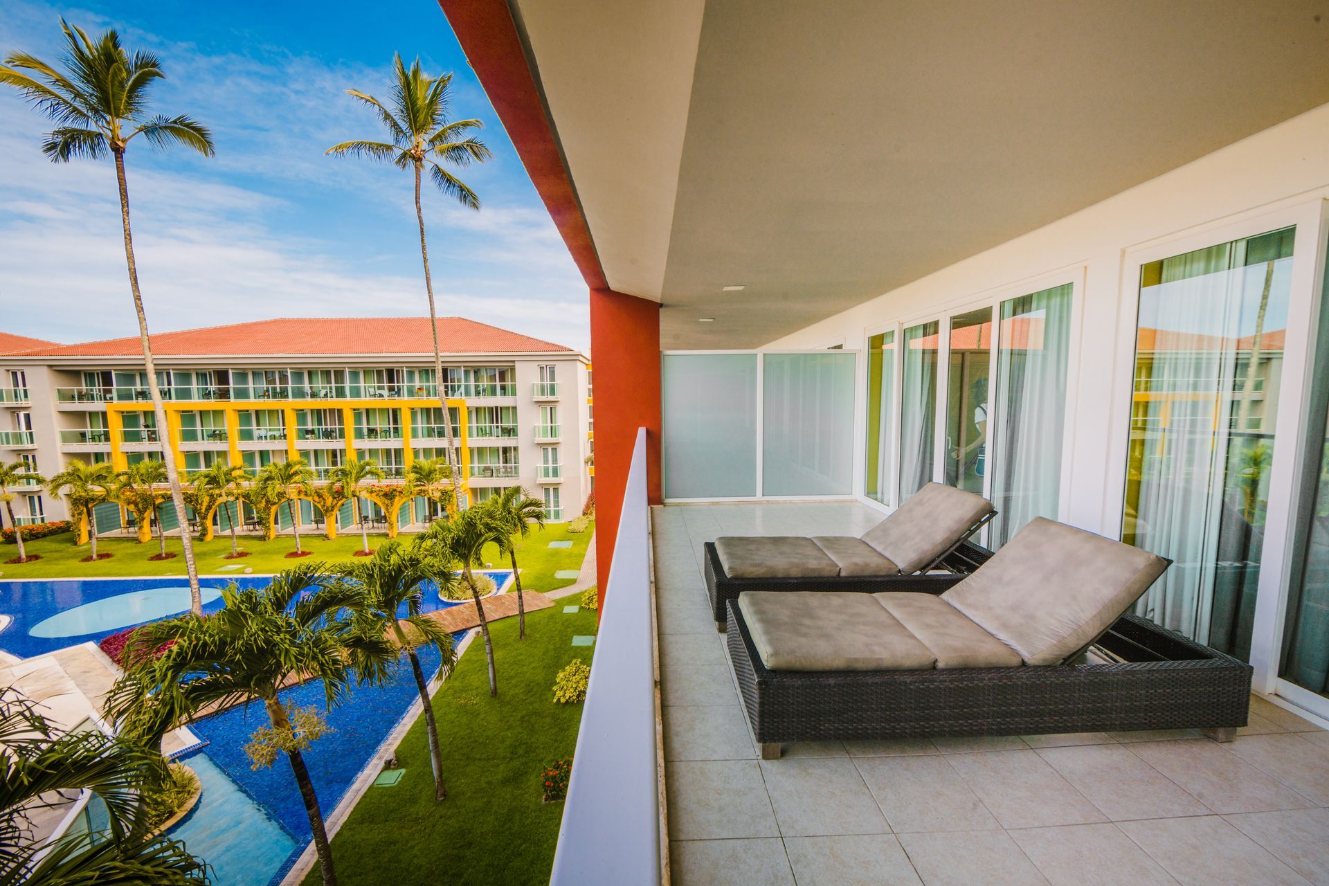 Luxury room balcony with a round table and chairs overlooking winding pools.