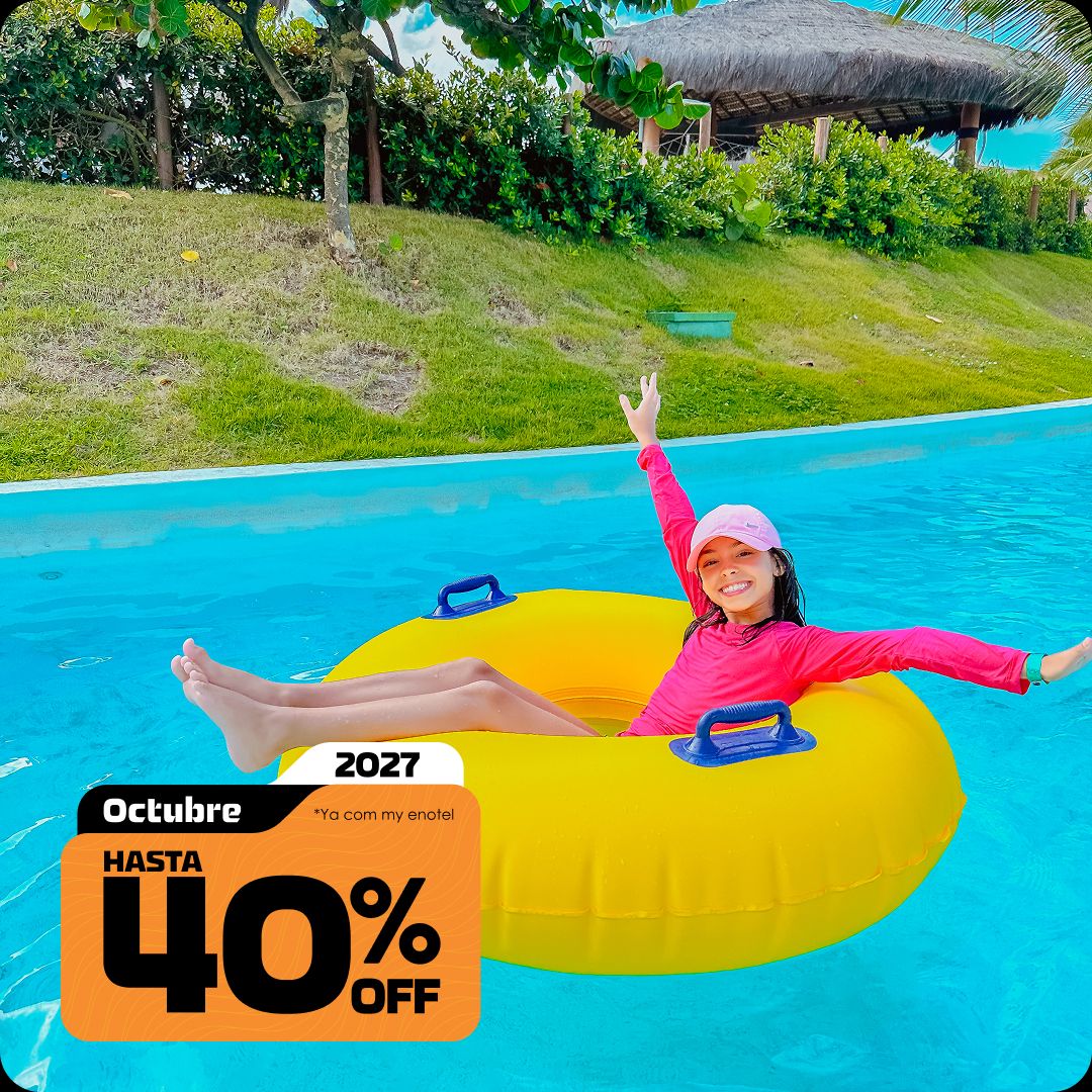 Menina sorrindo e acenando com os braços enquanto brinca em uma boia amarela no rio lento do resort Enotel, em um dia ensolarado. A imagem contém o selo da promoção My Black com até 40% de desconto para reservas em outubro de 2027.