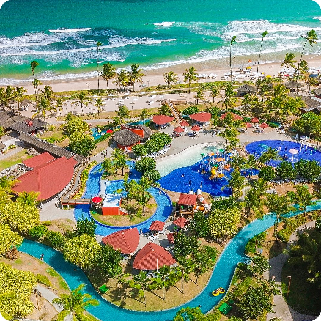 Vista aérea do imenso complexo de piscinas, parque aquático infantil e rio lento do resort Enotel Porto de Galinhas, de frente para o mar verdejante, perfeito para curtir os feriados prolongados de novembro.