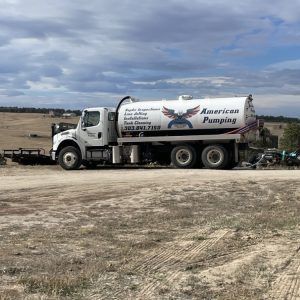 White pumping truck parked on a dirt lot under a cloudy sky, labeled “Americas Pumping.”