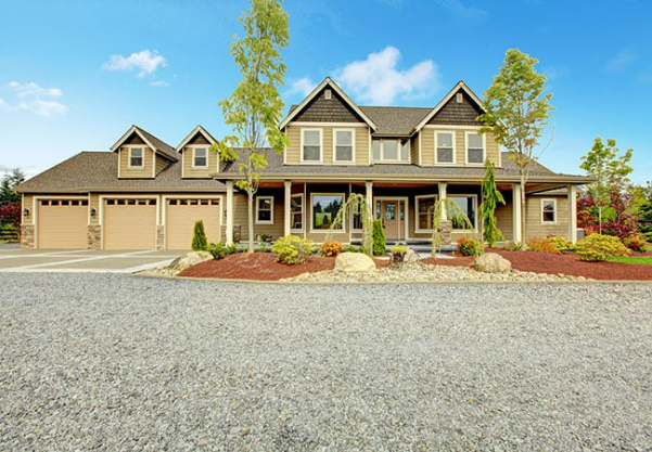A large house with a gravel driveway in front of it.