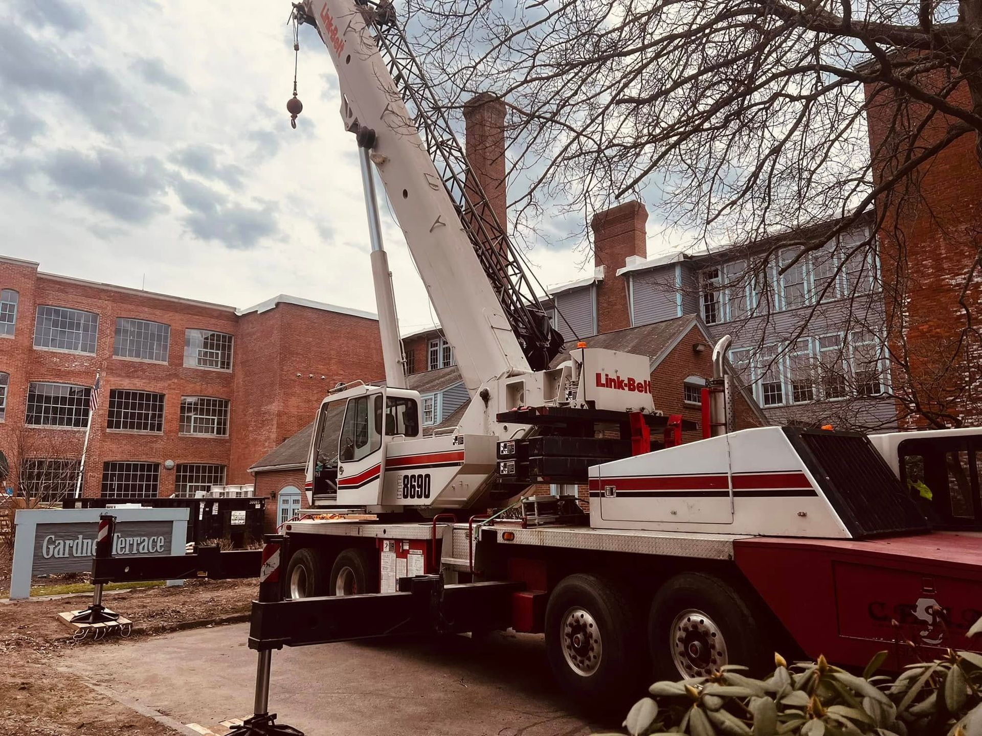 A large red and white crane is parked in front of a brick building.