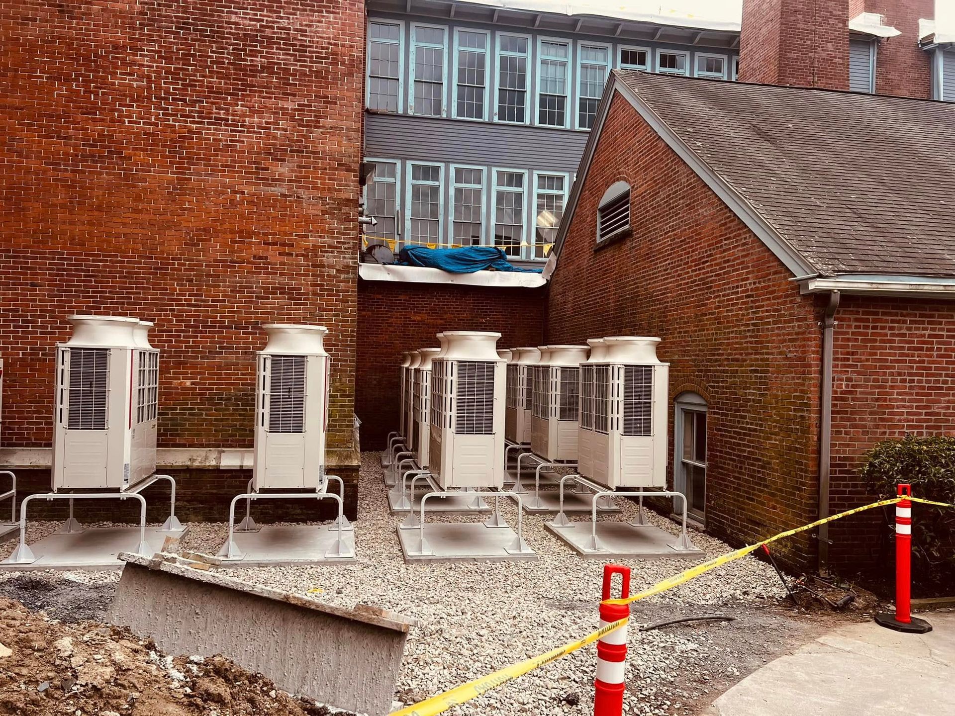 A row of air conditioners are sitting outside of a brick building.