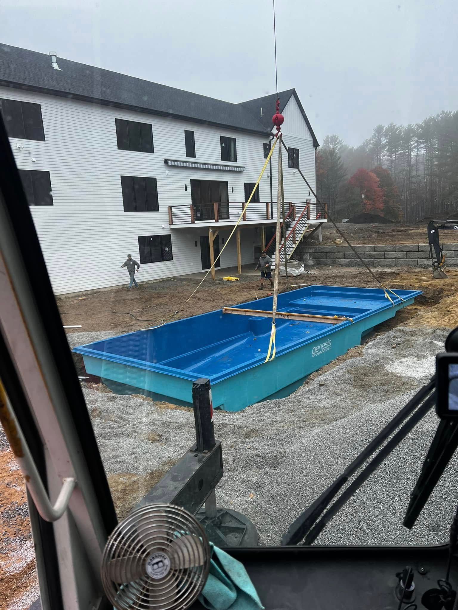 A swimming pool is being built in front of a large white building.