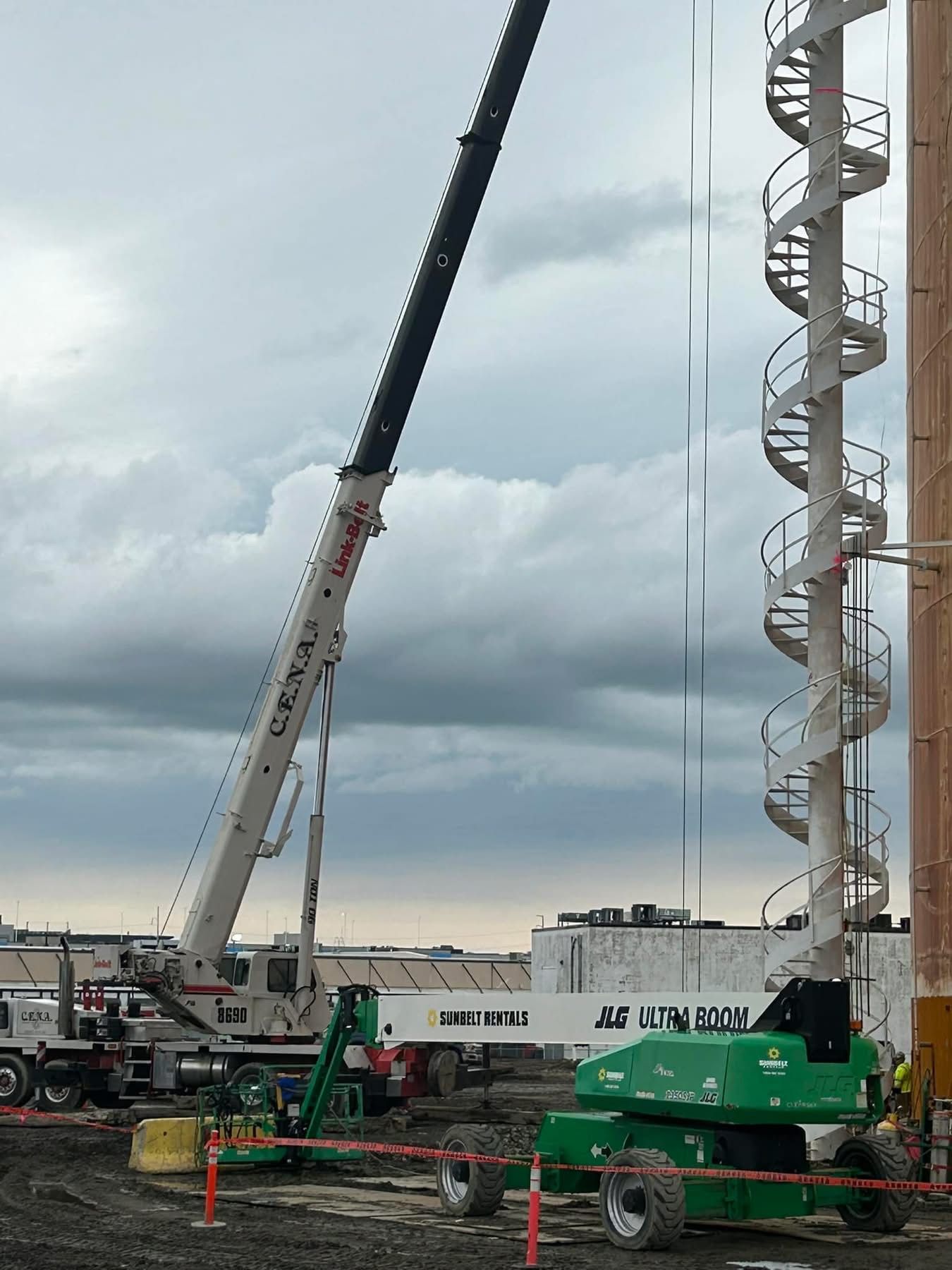 A large red and white crane is parked in front of a brick building.