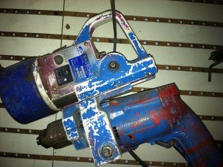A blue and red drill is hanging on a wall