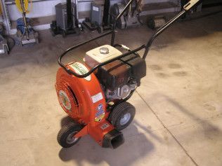 An orange blower is sitting on a concrete floor in a garage.