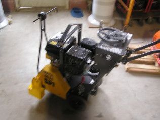 A yellow and black machine with a steering wheel is sitting on the floor.