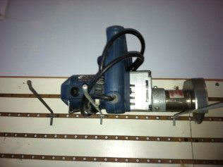 A blue and silver drill is hanging on a wall