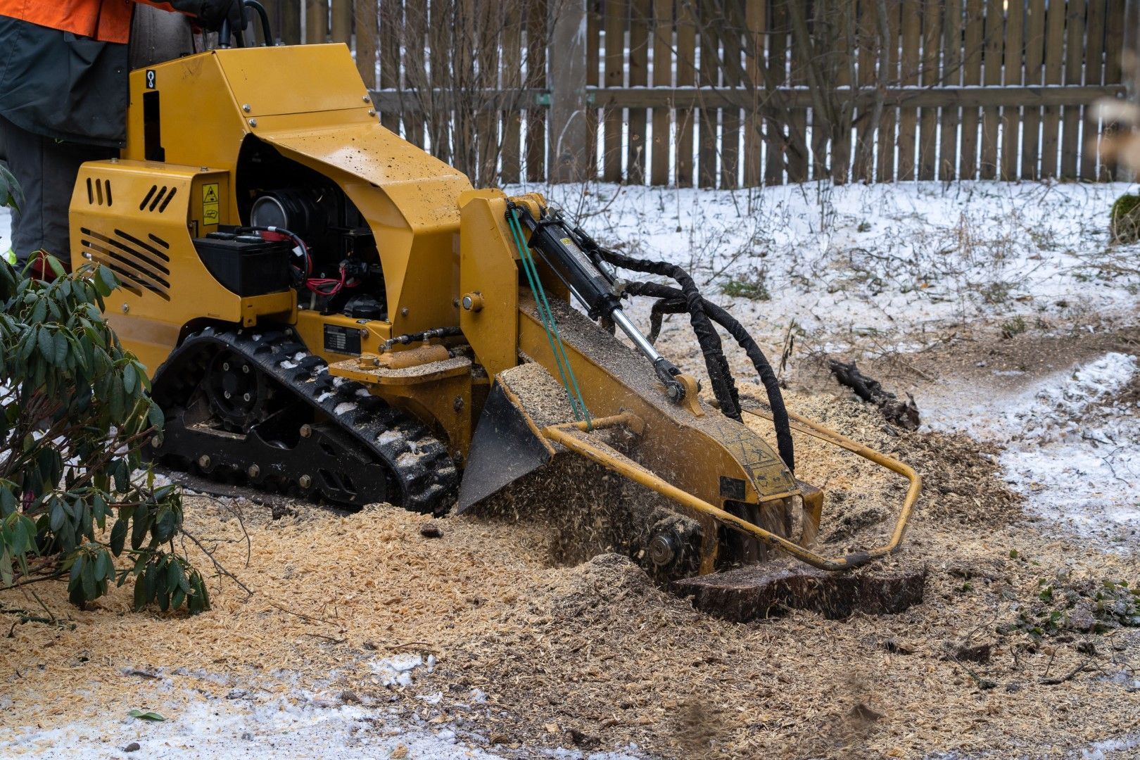 A man is using a stump grinder to remove a tree stump.