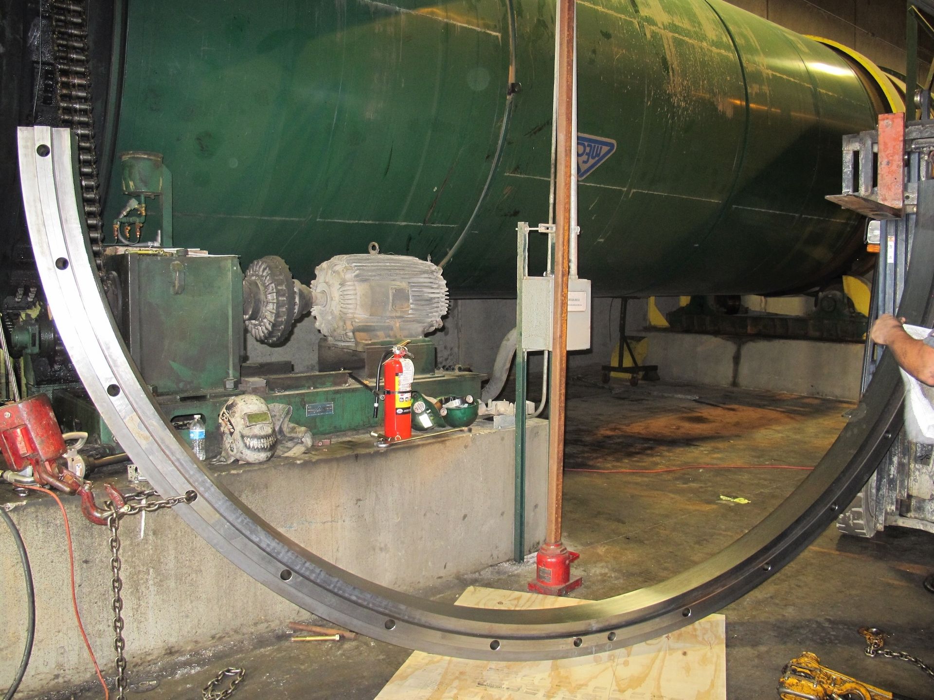 A man is working on a large metal ring in a factory