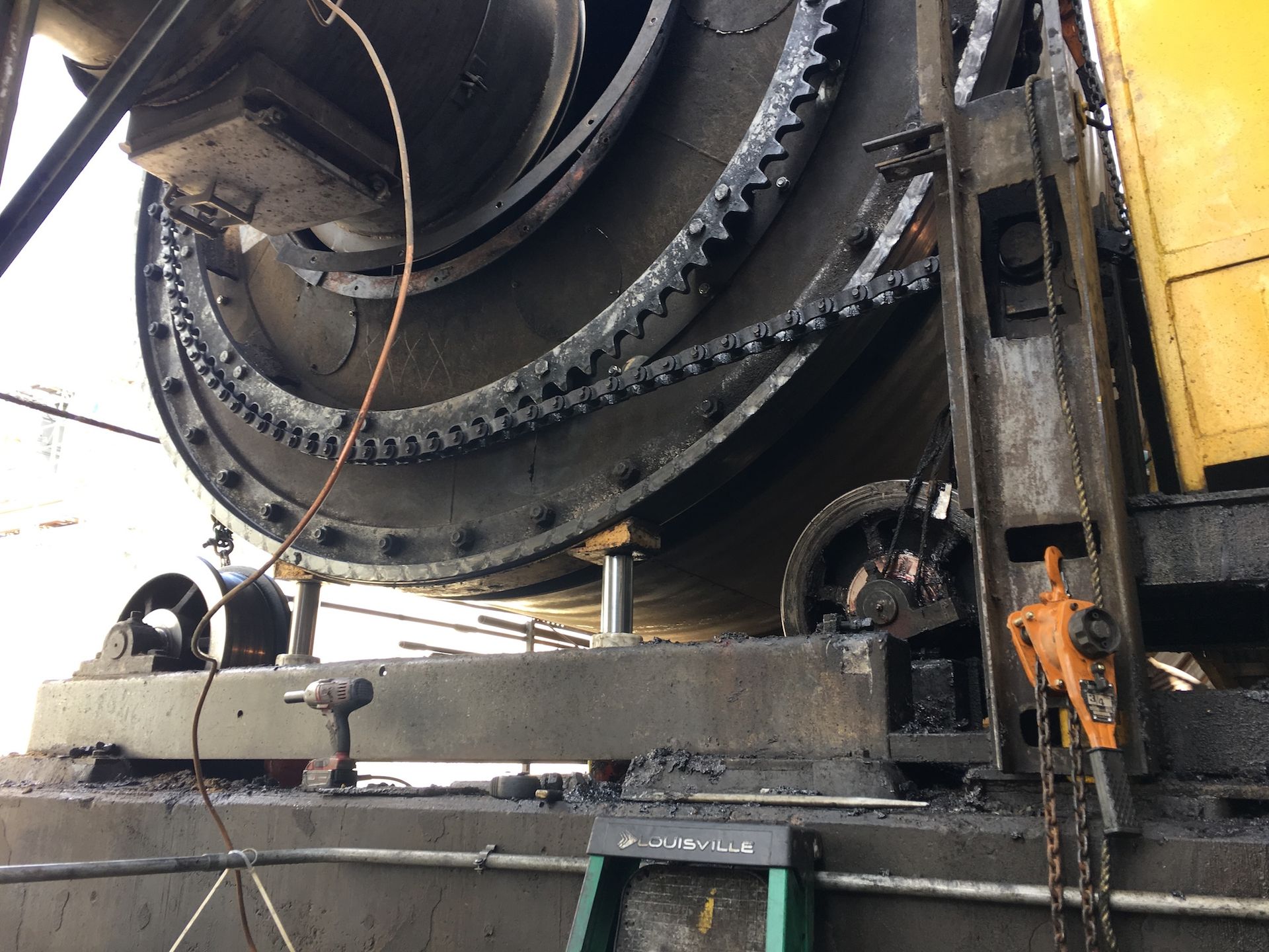 A large machine is sitting on top of a ladder in a factory.