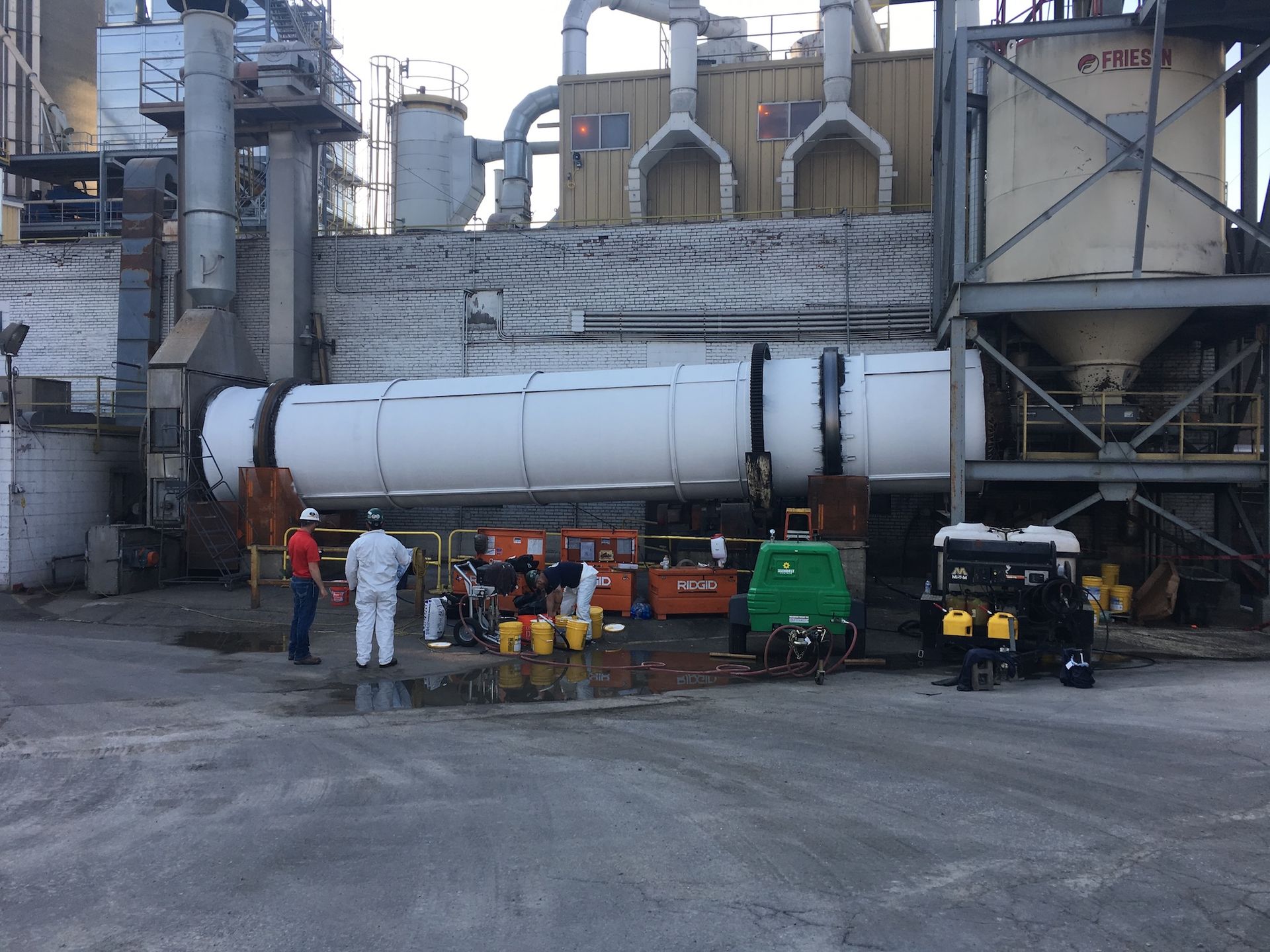 A group of people are standing in front of a large white tank that says 