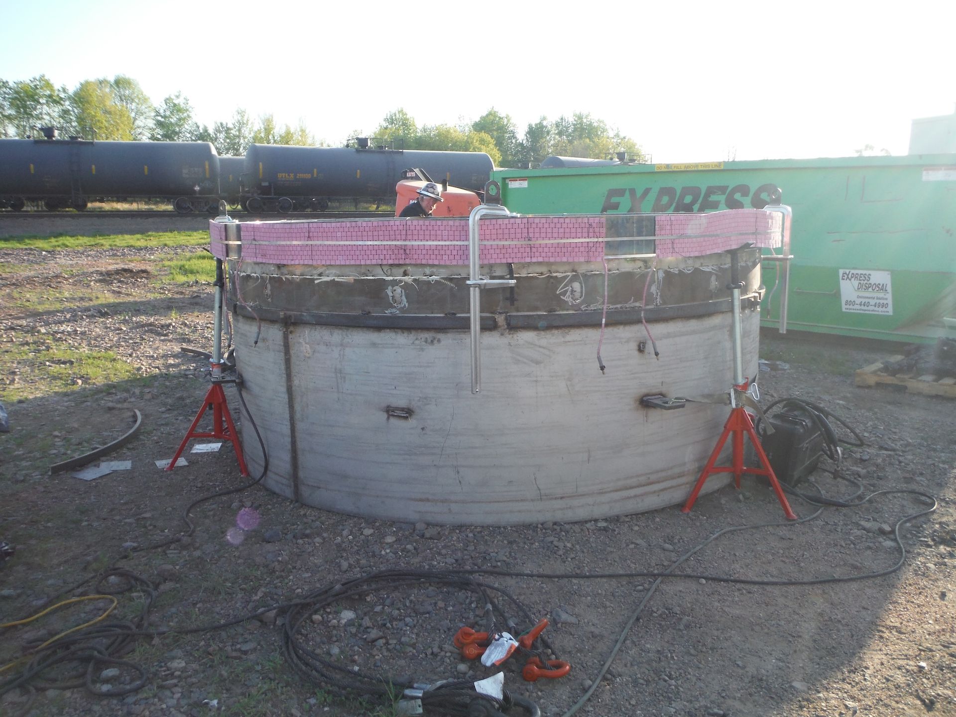 A green express container sits next to a large concrete cylinder