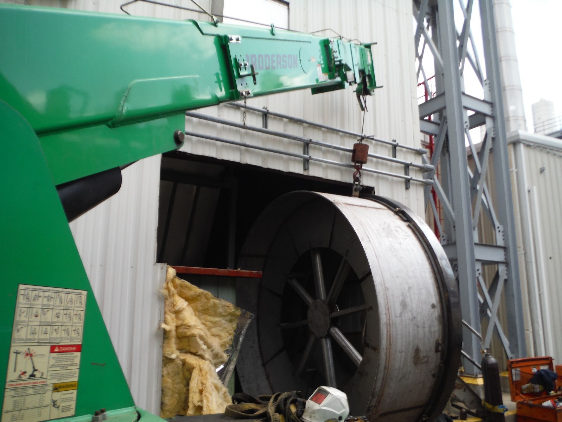 A green crane is lifting a large metal object