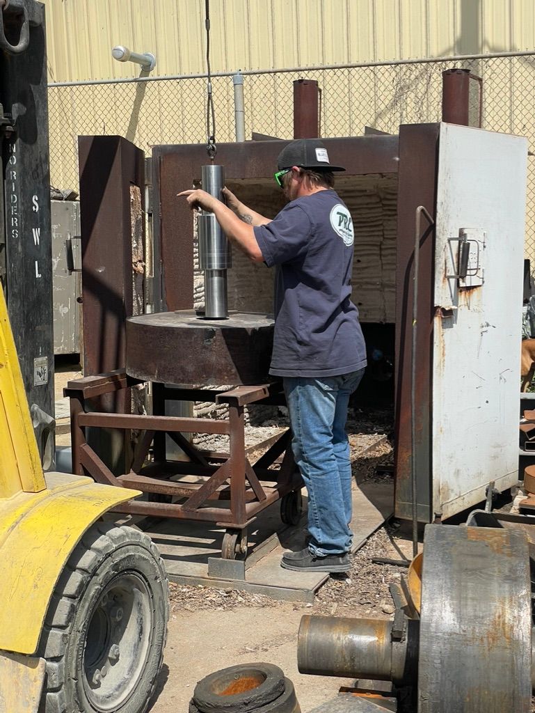 A man is standing in front of a machine with a forklift in the background.