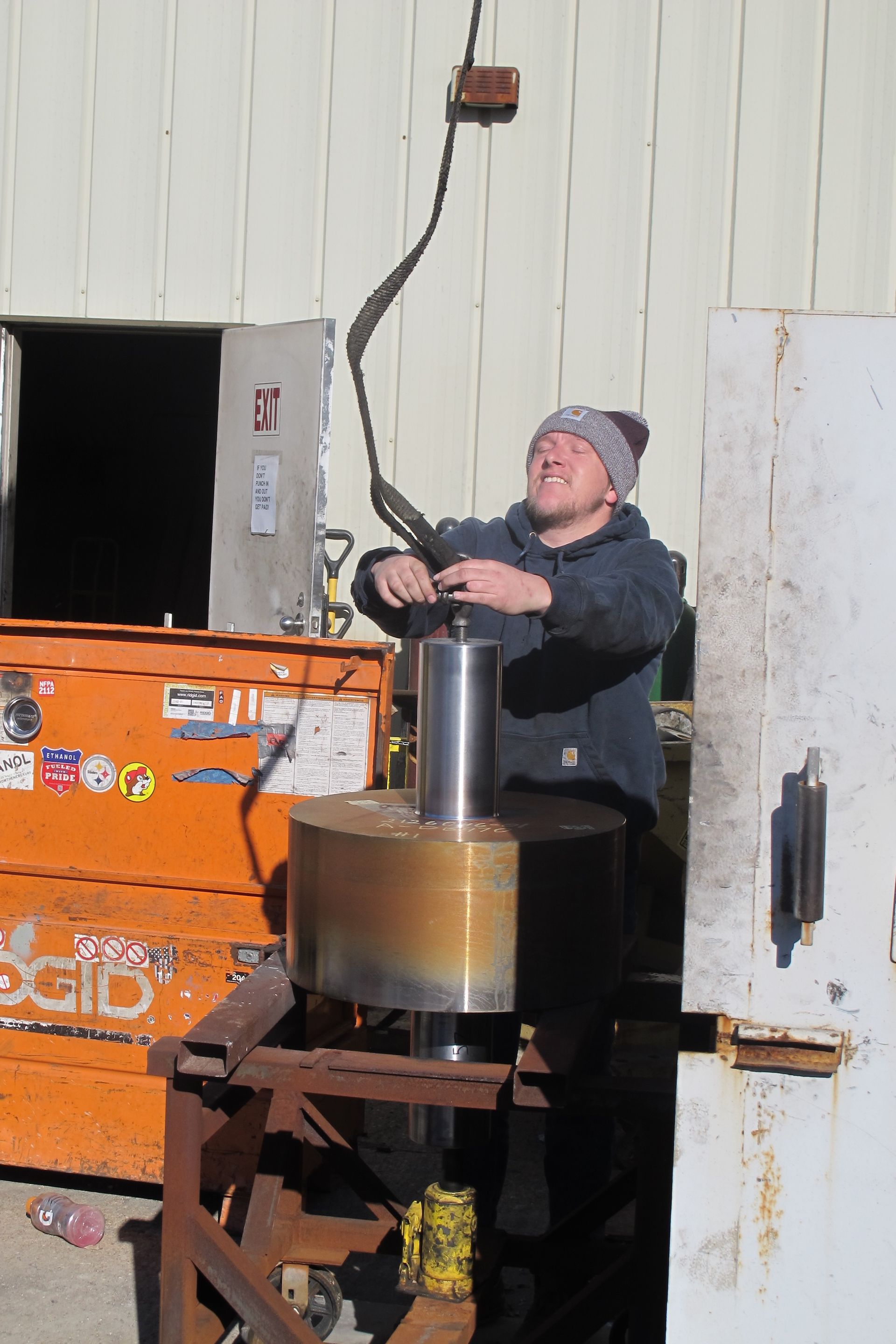A man is working on a machine in front of an orange box that says rigid